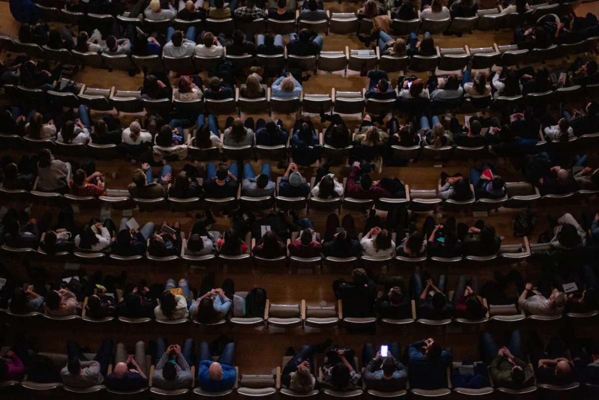 A large auditorium seen from above, most of its seats taken